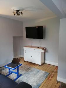 a living room with a tv and a table with a laptop at Entire House in Belfast