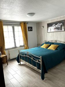 a bedroom with a bed with blue sheets and yellow pillows at Chambres et table d'hôtes Floromel La Souterraine en rez de chaussee in La Souterraine