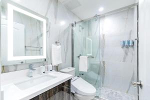 uma casa de banho branca com um lavatório e um chuveiro em Luxury 2BR Unit - Heart of the Chinatown em Toronto