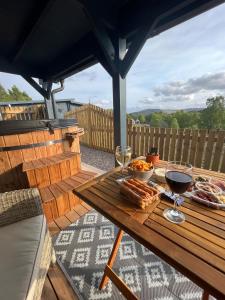 インバネスにあるRetreat Hot Tub Highland Cabinの木製テーブル(デッキ上の食べ物とワイン付)