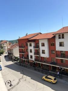 大特爾諾沃的住宿－Victoria Hotel Rooms Veliko Tarnovo &Victoria apartment，停在建筑物前的街道上的黄色汽车