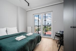 a bedroom with a green bed with towels on it at Warsaw Modern Stay Apartamenty Kasprzaka 29 in Warsaw