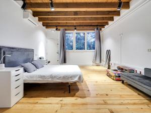 a bedroom with a white bed and a wooden floor at Bonita casa en parc Guell Barcelona in Barcelona