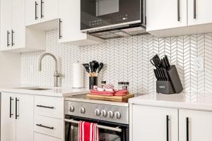 cocina con armarios blancos y estufa de acero inoxidable en Stylish 2BR Condo - Balcony - Stunning City View en Kitchener