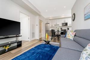 a living room with a gray couch and a tv at Stylish 2BR Condo - Balcony - Stunning City View in Kitchener