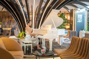 a woman sitting at a white piano in a lobby at Premier Pearl Hotel Vung Tau in Vung Tau