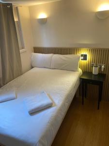 Una cama blanca con dos toallas encima. en Exhibition Court Hotel 4 en Londres