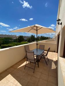 einen Tisch und Stühle auf einem Balkon mit Sonnenschirm in der Unterkunft Apartamento Panoramica Golf - Sant Jordi in San Jorge