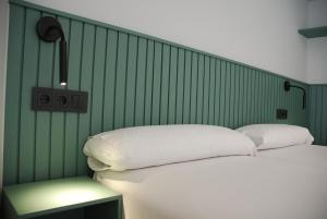a bedroom with a white bed and a green wall at Apartamentos Sunway Atlanta in Sitges