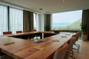 een conferentieruimte met een grote houten tafel en stoelen bij Boutique Hotel Blendin Bloemendaal aan Zee in Overveen