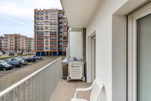 a balcony with a white chair and a building at Rembrandt Glv in Wenduine