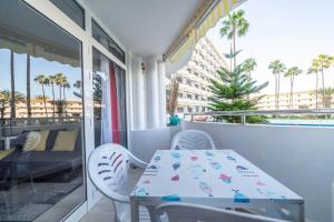 a table and chairs on a balcony with palm trees at Paraiso maspalomas sunset by CALIMA HOMES in San Bartolomé