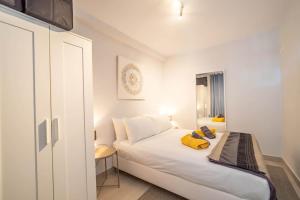 a bedroom with a white bed with a yellow towel on it at Paraiso maspalomas sunset by CALIMA HOMES in San Bartolomé +14 photos