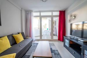 a living room with a couch and a television at Paraiso maspalomas sunset by CALIMA HOMES in San Bartolomé