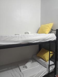 2 Etagenbetten in einem Zimmer mit gelben Kissen in der Unterkunft TMD COMFORTABLE TRANSIENT HOUSE IN STO.TOMAS BATANGAS in San Felix