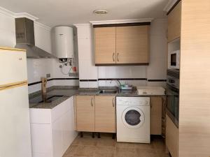 a kitchen with a washing machine and a sink at Luminoso ático en centro ciudad - Alquiler de temporada in Puerto de Sagunto +8 photos