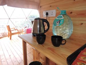 a tea kettle and two cups on a counter at L.T NATURE GLAMPS in Kodaikānāl