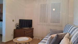 a living room with a couch and a television on a dresser at Apartments Stana in Sukošan