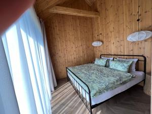 a bed in a room with a wooden wall at Viesuli Village Villa in Saraiķi
