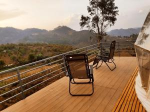 two chairs sitting on a deck with a view of mountains at L.T NATURE GLAMPS in Kodaikānāl