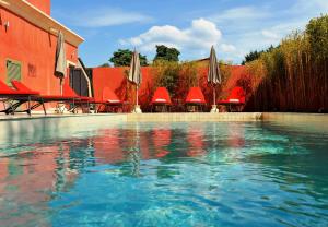 una piscina con sombrillas, mesas y sillas en Hôtel Liberata & Spa en LʼÎle-Rousse