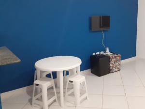 皮烏馬的住宿－Apartamento 101 com vista da piscina e mar，蓝色墙壁的房间里一张白色的桌子和凳子