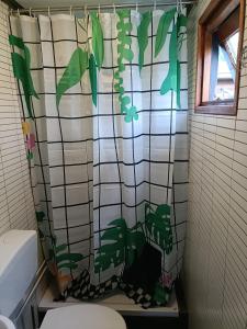 baño con cortina de ducha con plantas. en Vakantiehuisje Veluwe bij Speuldersbos, en Putten