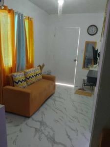ein Wohnzimmer mit einem Sofa und einer Uhr in der Unterkunft TMD COMFORTABLE TRANSIENT HOUSE IN STO.TOMAS BATANGAS in San Felix