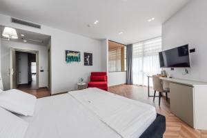 a bedroom with a bed and a desk and a red chair at Polifonia City Loft - Hotel rooms Vlorë, Albania in Vlorë
