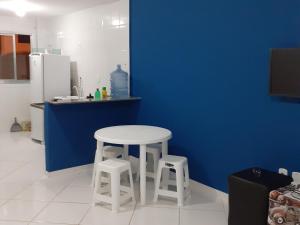 a kitchen with a white table and two stools at Apartamento 101 com vista da piscina e mar in Piúma