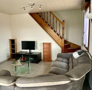a living room with a couch and a television at Maison Les Tilleuls in Les Pontets