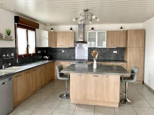 a kitchen with wooden cabinets and a kitchen island with chairs at Maison Les Tilleuls in Les Pontets