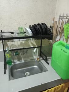 eine Küchentheke mit einer Spüle und einem Regal mit Küchenutensilien in der Unterkunft TMD COMFORTABLE TRANSIENT HOUSE IN STO.TOMAS BATANGAS in San Felix