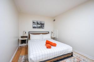 ein Schlafzimmer mit einem weißen Bett mit zwei orangefarbenen Kissen in der Unterkunft Modern 2BR Apt - Close to Trinity Bellwoods Park in Toronto