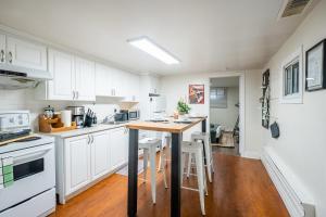 eine Küche mit weißen Schränken und einem Holztisch in der Unterkunft Modern 2BR Apt - Close to Trinity Bellwoods Park in Toronto