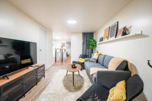 ein Wohnzimmer mit einem Sofa und einem Flachbild-TV in der Unterkunft Modern 2BR Apt - Close to Trinity Bellwoods Park in Toronto