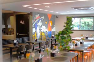 a restaurant with tables and chairs with a painting on the wall at WA HOTEL FORTALEZA in Fortaleza