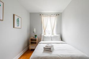 1 dormitorio con 1 cama blanca y ventana en Pet-Friendly 3BR Apartment - Ossington Ave en Toronto