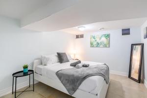 a white bedroom with a bed and a mirror at 2 Bedroom Apartment in the Heart of Trinity Bellwoods in Toronto