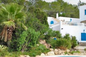 a white house with a palm tree in front of it at 5 bedrooms villa at Sant Josep de sa Talaia 900 m away from the beach with sea view private pool and enclosed garden in Sant Josep de Sa Talaia