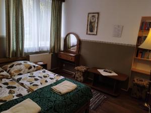 1 dormitorio con cama, espejo y mesa en Ódon Panzió en Bükkszentkereszt