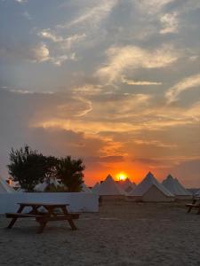einen Sonnenuntergang mit einem Tisch und Zelten in der Wüste in der Unterkunft Faleza23 in Olimp