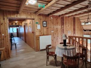 Cette chambre dispose d'une table, de chaises et de murs en bois. dans l'établissement Ódon Panzió, à Bükkszentkereszt