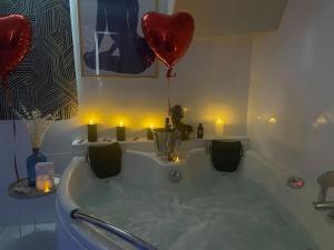 a bathroom with a tub with a heart balloon and candles at L'Escapade marine appartement avec jacuzzi privé in Cayeux-sur-Mer