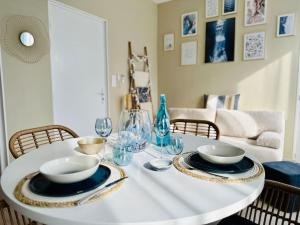 a white table with plates and wine glasses on it at L'Escapade marine appartement avec jacuzzi privé in Cayeux-sur-Mer