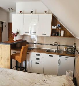 - une cuisine avec des placards blancs, un lavabo et un lit dans l'établissement Apartman Pavle, à Nova Varoš