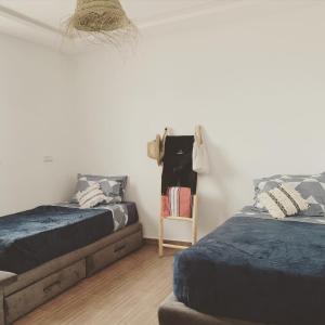 a bedroom with two beds and a clothes rack at W Surf Morocco in Agadir