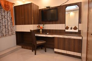 Zimmer mit einem Schreibtisch, einem TV und einem Stuhl in der Unterkunft HOTEL GITANJALI in Māldah