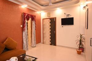 ein Wohnzimmer mit einem Sofa und einem TV an der Wand in der Unterkunft HOTEL GITANJALI in Māldah