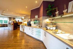 a large kitchen with white cabinets and purple walls at Hotel Diana in Bad Bentheim